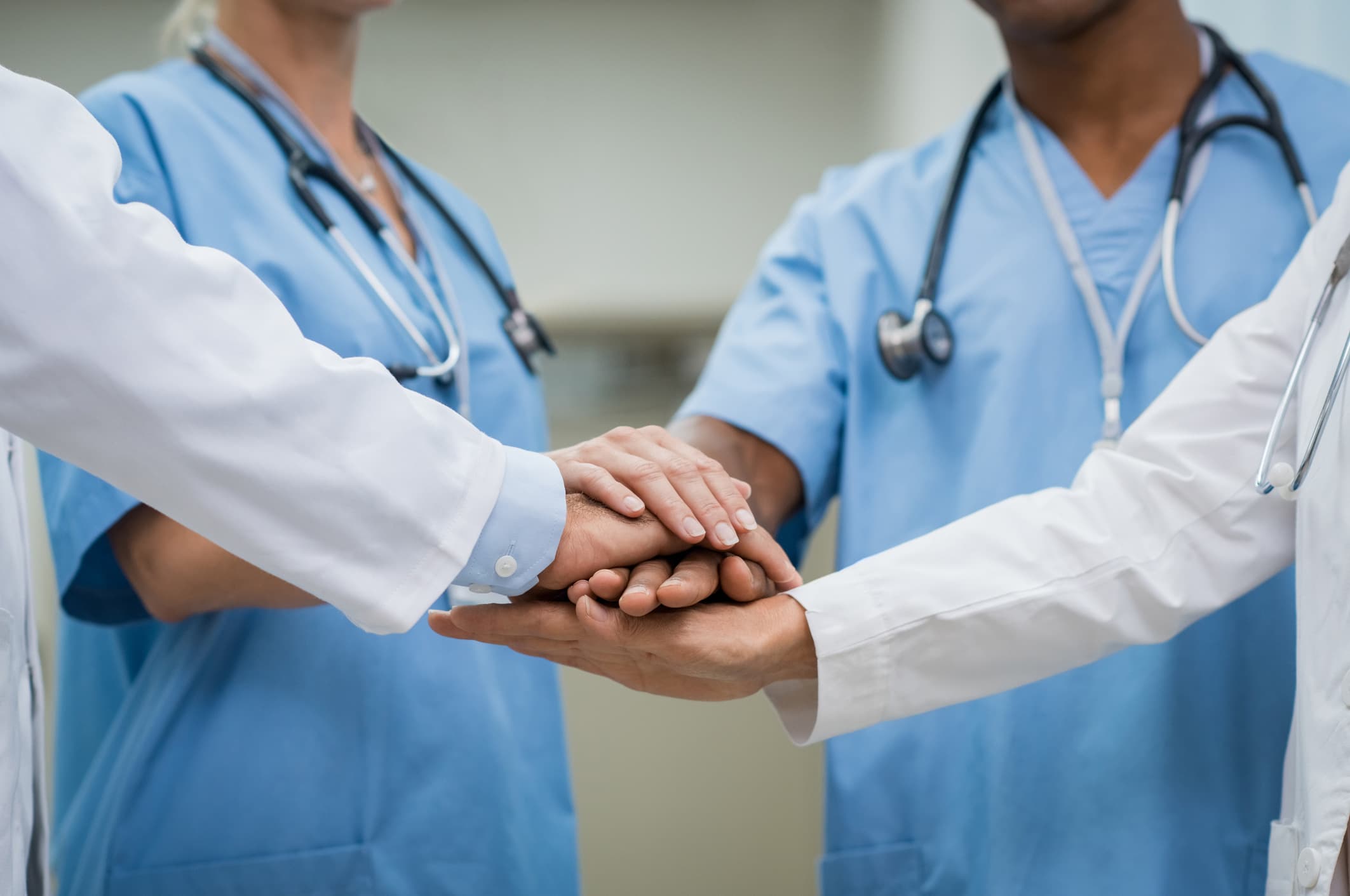 Group of doctors in a huddle with hands in the center