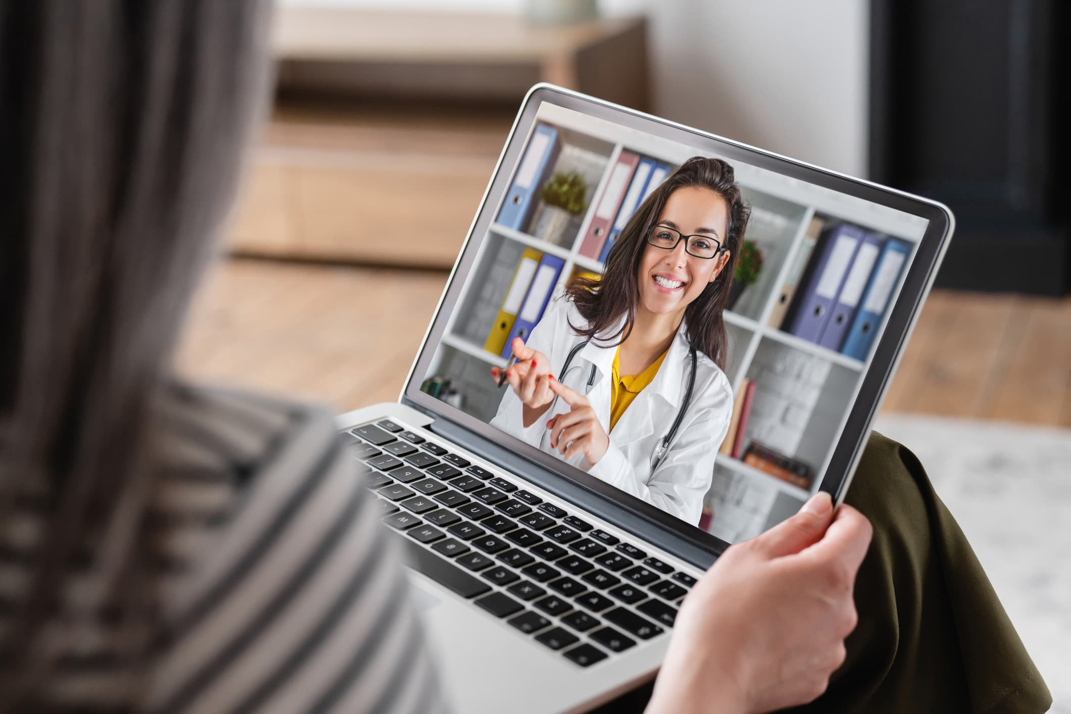 Woman holding laptop with doctor on the screen